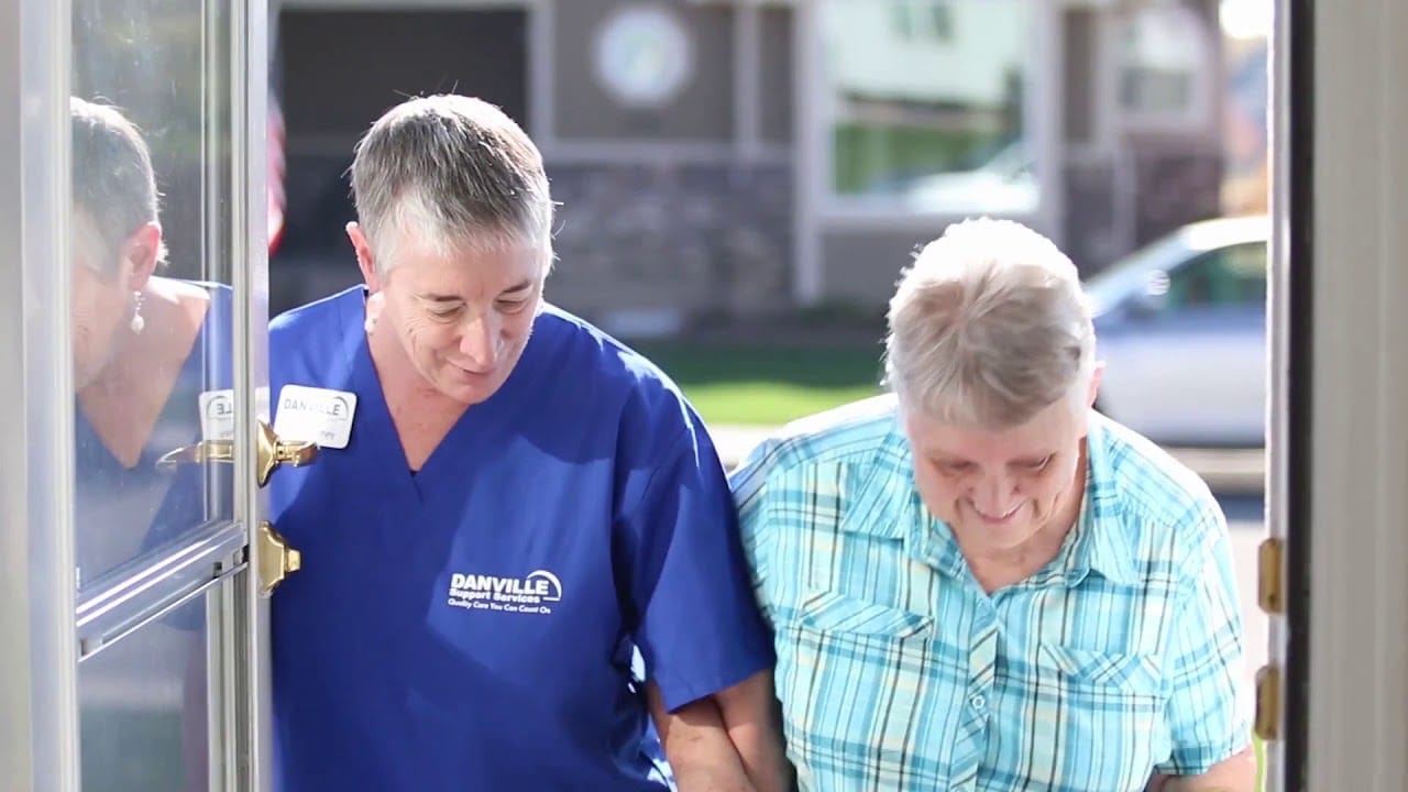 Danville Support Services staff member helping elderly woman through door